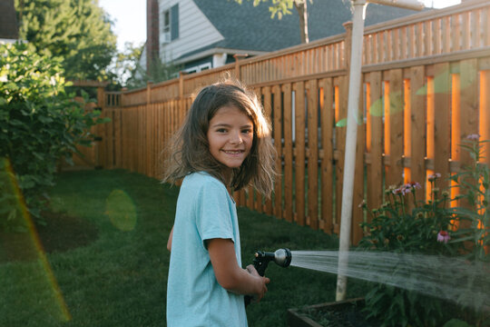 girl waters backyard garden