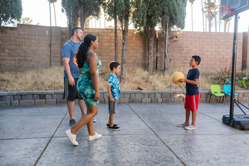 Family playing basketball in backyard