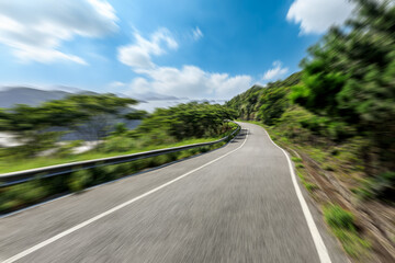 Fast moving asphalt road and green mountain natural scenery