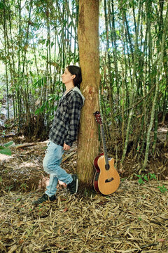 Musician leaning on a tree with his instrument
