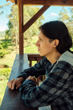 Young Latino man leaning on a wooden surface