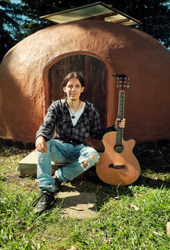Portrait of guitarist sitting in front of an igloo