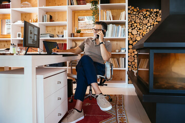 Cheerful freelancer writing down data during phone call