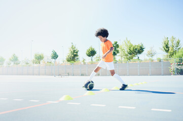 Young boy learning how to dribble and score a goal with Netherlands national football team equipment. Playing football in a training field. 