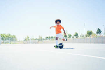 Young boy learning how to kick and score a goal with Netherlands national football team equipment. Playing football in a training field. 