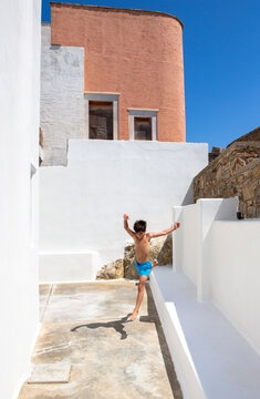 Eleven years old boy jumping among traditional houses