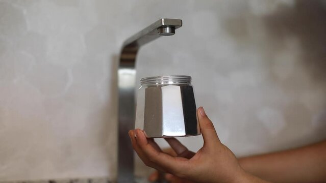 person putting water into a coffee pot