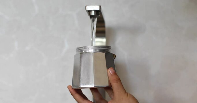 person putting water into a coffee pot