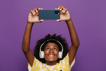Black child in headphones taking selfie