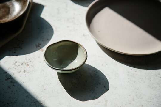 Empty bowls and plates on a table in hard light.