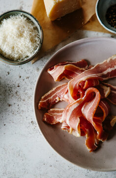 Rashers of streaky bacon, with grated parmesan and pepper.