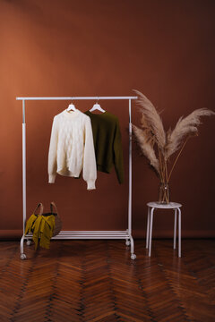 Two colorful sweaters on hangers