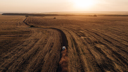 dusty trace behind a car speeding across the gravel road, drone view