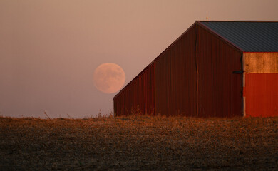 red barn and silo at sunset with a moon