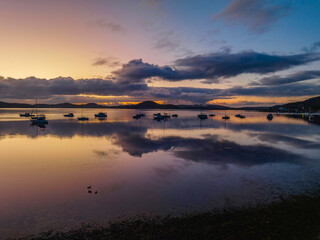 Aerial sunrise waterscape with boats, rain clouds and reflections