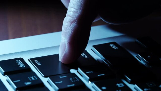 パソコンのキーボードのエンターキーを押す男性の指