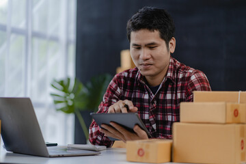 Young Asian men start selling online with boxes and laptops for taking orders and shipping parcel boxes, SME business idea.