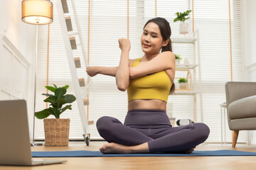 Young Asian woman doing yoga stretching yoga at home.Happy people stay home, doing aerobic exercise at living room Girl doing lockdown activity, workout with trainer for health in house.