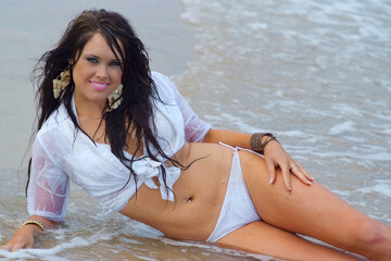 Beautiful brunette bikini girl posing on beach