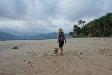 A woman walking with puppy at Pulau Merah beach in Banyuwangi, East Java, Indonesia,