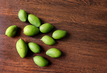 Small green mangoes on a wooden table