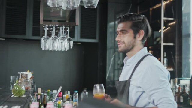 Two beautiful asian female businesswoman lady drink cocktail together and chit chatting about life in a rooftop bar after a long day work and a handsome bartender male waiter join the conversation