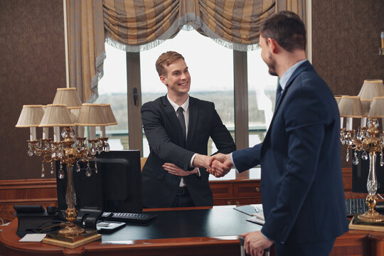 Smiling hotel receptionist helping Businessman to check in and receive key from room