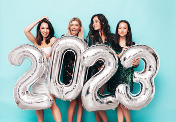 Beautiful women celebrating New Year. Happy gorgeous female in stylish sexy party dresses holding...