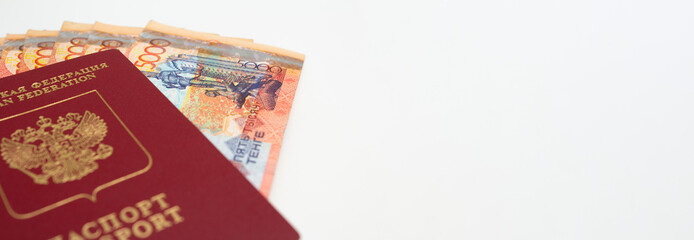 Banner with paper money of the Republic of Kazakhstan in a Russian passport. A stack of banknotes in 5000 Kazakh tenge. Relocation and immigration from Russia due to war in Ukraine and mobilization