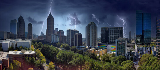 an aerial panoramic shot of the skyscrapers and office buildings in the city skyline surrounded by lush green trees with storm clouds and lightning in downtown Atlanta Georgia USA