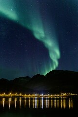 Vertical shot of Northern Lights over the mountains in Norway during the stary night