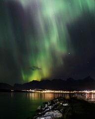 Vertical shot of Northern Lights over the mountains in Norway during the stary night