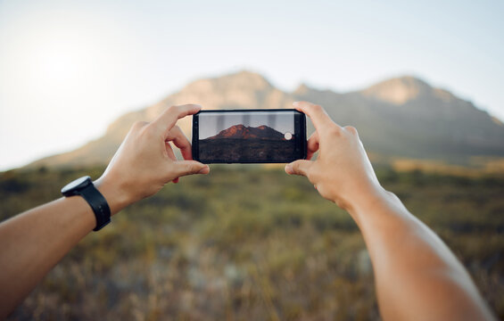 Hands, phone and mountain picture in nature for adventure, travel and countryside in the outdoors. Hand of traveler taking a photo of the natural environment with mobile smartphone in South Africa