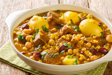 Close-up of Traditional Jewish Cholent Hamin main dish for the Shabbat meal, slow cooked beef with potato, beans and brown eggs  closeup in the pan on the table. Horizontal