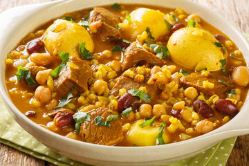 Jewish Cholent Hamin prepared is Israel as the main dish for the Shabbat meal made with beef, potato, beans, barley, and more  closeup in the pan on the table. Horizontal