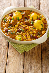 Traditional Jewish Cholent Hamin main dish for the Shabbat lunch, slow cooked beef with potato, beans, brown eggs,  barley closeup in the pan on the table. Vertical