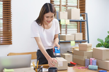Online selling concept, Asian business women packing product into parcel box and sealing with tape