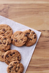 Raisin cookies placed on white paper served on a wooden table.