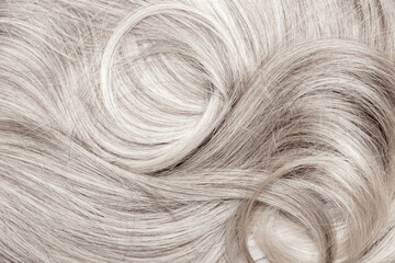 Blond hair close-up as a background. Women's long blonde hair. Beautifully styled wavy shiny curls....
