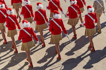 A group of girls with drums march in formation at the parade. The drummers are dressed in red...