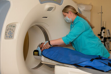 A doctor in a medical gown prepares a patient for magnetic resonance imaging MRI computed...