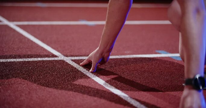 someone is preparing to sprint in a sports stadium by night with lights