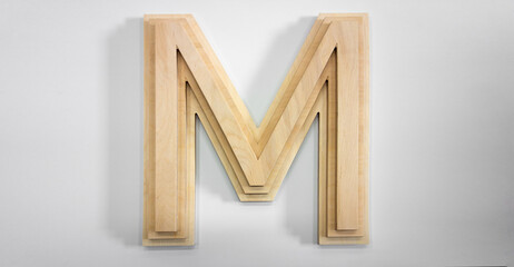 Wooden letter M on a white background. The letter is made of wooden parts.