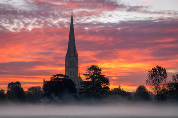 Obraz premium October misty morning sunrise behind Salisbury Cathedral from the Harnham water meadows Wilitshire south west England