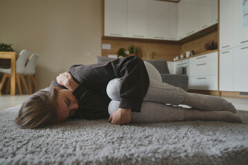Naklejka premium Caucasian woman lying down at the carpet in home with mental problem
