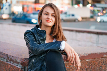 Portrait young beautiful fashionable redhead woman with freckles, long curly hair, in casual youth clothes, posing on a city street. With a sad expression