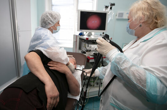 A female doctor holds an endoscope during a gastroscopy for a hospital patient. Medical office for diagnosing abdominal pain.