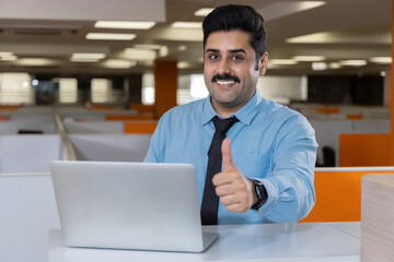 Smiling businessman showing thumbs up in his office.