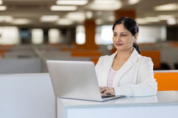 Businesswoman using laptop on sofa at office