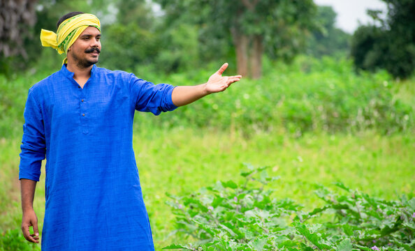 Young indian farmer standing in green agriculture field